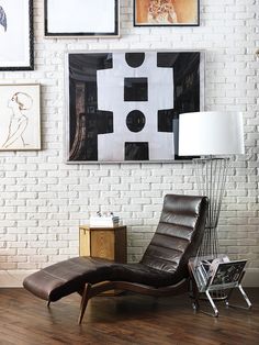 a chair sitting in front of a white brick wall with pictures on the wall behind it