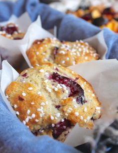 two blueberry muffins with white sprinkles in wrappers on a table