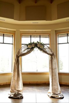 an image of a wedding arch in the middle of a room with windows and curtains