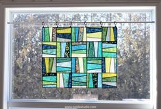 a stained glass window with trees in the background and string hanging from it's side