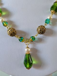 Peridot glass bead necklace. A beautifully handmade necklace with faceted glass teardrop beads as well as a mix of vintage brass filigree beads and faux pearls. This necklace is finished with a delicate chain and a push fit fastener, measuring roughly 18 inches in length. Beaded Czech Glass Pendant Necklace, Wire Wrapped Czech Glass Dangle Necklaces, Green Beaded Necklace With Pearl Drop For Gift, Wire Wrapped Czech Glass Pendant Necklace, Czech Glass Beaded Chain Dangle Necklaces, Czech Glass Beaded Chain Dangle Necklace, Czech Glass Dangle Necklaces With Dangling Beads, Green Czech Glass Necklaces With Faceted Beads, Green Elegant Dangle Crystal Necklaces