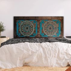 a bed with white sheets and blue decorative artwork on the headboard in a bedroom