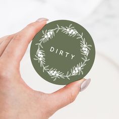 a hand holding a green sticker with the word dirty written in white on it