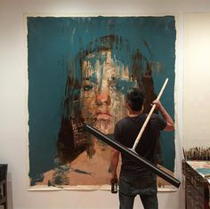 a man is holding a large painting in front of him