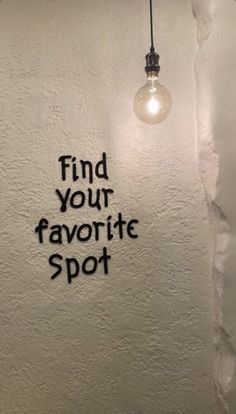 a white wall with black writing on it and a light bulb hanging from the ceiling