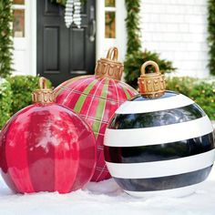 three christmas ornaments sitting in the snow next to a black and white striped ornament