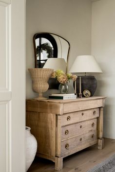 a wooden dresser with a mirror and lamp on top