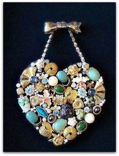 a heart shaped purse with many different types of beads and stones on the front, hanging from a chain