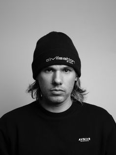 a man with long hair wearing a black shirt and a beanie on his head