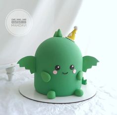 a green cake with a crown on it's head sitting on top of a table