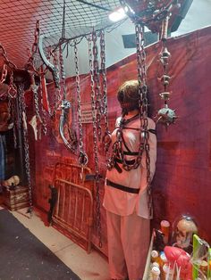 a woman standing in front of a red wall with lots of chains hanging from it