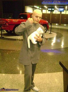 a man holding a white cat in his hands at an airport lobby with other vehicles behind him