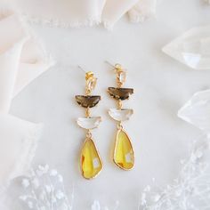 "These gorgeous boho bridal earrings feature unique faceted yellow drops which are reminiscent to flower petals or even fluttering butterfly wings! These eye catching statement earrings are the perfect accessory for wearing in an updo hair style for your boho wedding, a birthday gift for your best friend or to add a touch of sparkle for a special occasion this summer! These dangle earrings are created with sterling silver and oval faceted glass with a golden frame. Your beautiful yellow and hazel brown earrings will arrive suitably gift wrapped ready for gift giving. Measurements: The length of the boho bridal earrings hang just under 2.5\" long Metals: 18k gold plated brass  925 sterling silver plated earring posts For a similar pair of earrings with pink and hazel brown: https://www.etsy Yellow Teardrop Earrings For Wedding, Faceted Yellow Jewelry For Wedding, Yellow Faceted Dangle Earrings, Yellow Dangle Chandelier Earrings For Wedding, Yellow Wedding Earrings With Ear Wire, Yellow Ear Wire Earrings For Wedding, Yellow Earrings With Ear Wire For Wedding, Yellow Dangle Earrings For Wedding, Yellow Teardrop Faceted Earrings