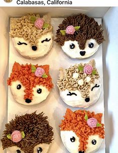 four cupcakes decorated like hedgehogs with flowers on them in a box