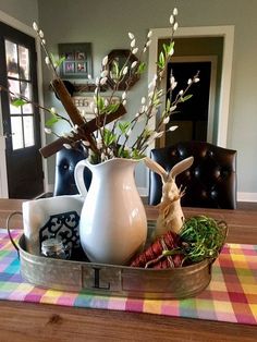 a white pitcher filled with flowers sitting on top of a table next to other items