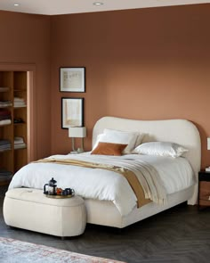 a bedroom with a bed, ottoman and shelves on the wall in front of it