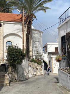 an alley way with palm trees and white buildings