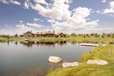 a large house sitting on top of a lush green field next to a lake