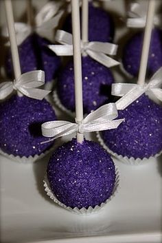 purple cake pops with white bows and ribbons on a plate, ready to be eaten