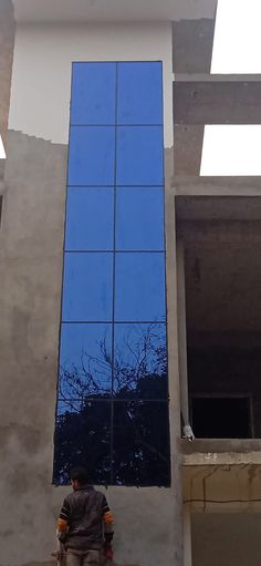 a man sitting on a step in front of a tall building with windows reflecting the sky