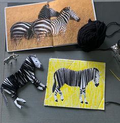 two zebras are next to each other on a table with yarn and crochet