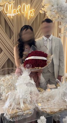 a man and woman standing next to each other in front of a table with flowers