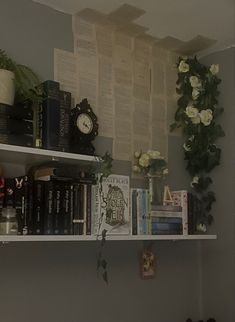 a shelf with books, flowers and other items on it next to a wall mounted clock