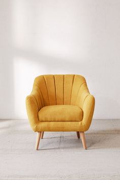 a yellow chair sitting on top of a cement floor next to a white brick wall