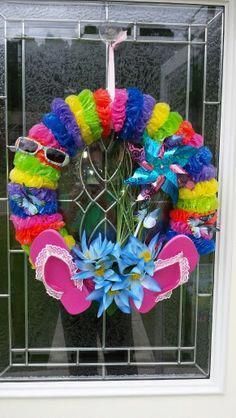 a colorful wreath with flip flops, sunglasses and flowers in front of a window