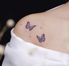 two pink butterflies on the back of a woman's shoulder, with stars in the background