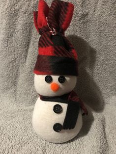 a stuffed snowman wearing a red and black hat, scarf and scarf around it's neck