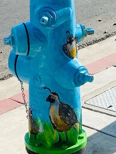 a blue fire hydrant with two birds painted on it