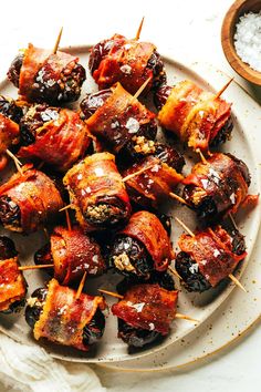 bacon wrapped dates are on a plate with toothpicks in the middle and other food items