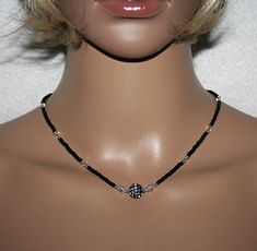 This elegant necklace consists of black Rocailles, Swarovski Crystal beads and silver Miyuki Rocailles. The middle adorns a black pearl, which is equipped with many small sparkling stones. To the right and left of this pearl are 2 crystal pearls with a rhinestone rondel.  Very delicate, light and comfortable to wear, this necklace is a fascinating accessory for special occasions.  The lobster clasp is made of sterling silver 925.  Properties: Rocailles 2.5mm, black and silver  Swarovski Crystal Elegant Crystal Necklace With Black Beads For Gift, Elegant Black Beaded Crystal Necklace For Gift, Black Beaded Pearl Necklace For Wedding, Adjustable Black Beaded Necklace For Wedding, Elegant Black Beads Choker As Gift, Handmade Black Necklaces For Wedding, Elegant Black Crystal Necklace As Gift, Elegant Black Beads Choker For Gift, Black Single Strand Necklace For Gift