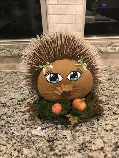 a hedgehog statue sitting on top of a counter next to an orange and pine cone