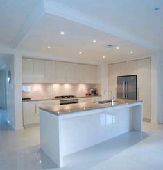 a large kitchen with an island in the middle and white cabinets on both sides is lit by recessed lights