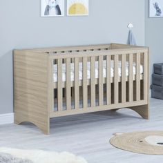 a baby's room with a crib, rug and pictures on the wall