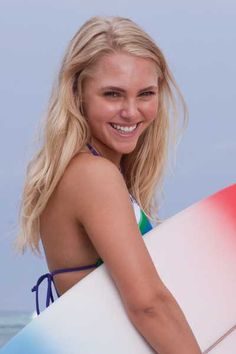 a woman holding a surfboard on the beach