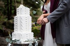 a bride and groom cutting their wedding cake with a knife in front of the couple