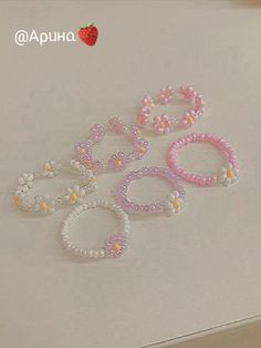 five bracelets with flowers and pearls on them sitting on top of a white table