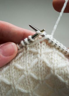 someone is knitting the stitchs on their sweater