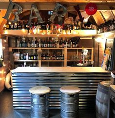 the bar has three stools in front of it and several bottles on the shelves