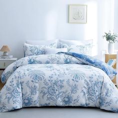 a bed with blue and white comforters in a room next to a lamp on a table