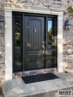 a black front door with two sidelights on the brick wall and an entry mat