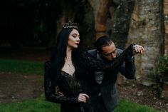 a man and woman dressed in black are posing for a photo together on the grass