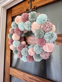 a wreath with pom - poms hanging on the front door