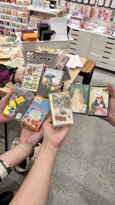 two hands holding small cards in front of a table with many other items on it