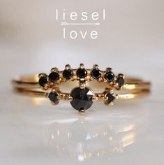 two gold rings with black stones on them and the words liessel love written in white lettering