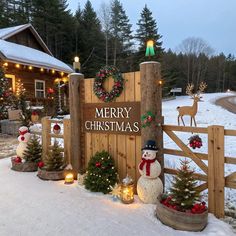 a wooden fence with christmas decorations and lights on it in front of a house decorated for the holiday season