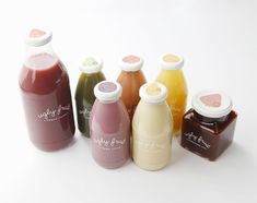 six bottles of juice are lined up on a white surface